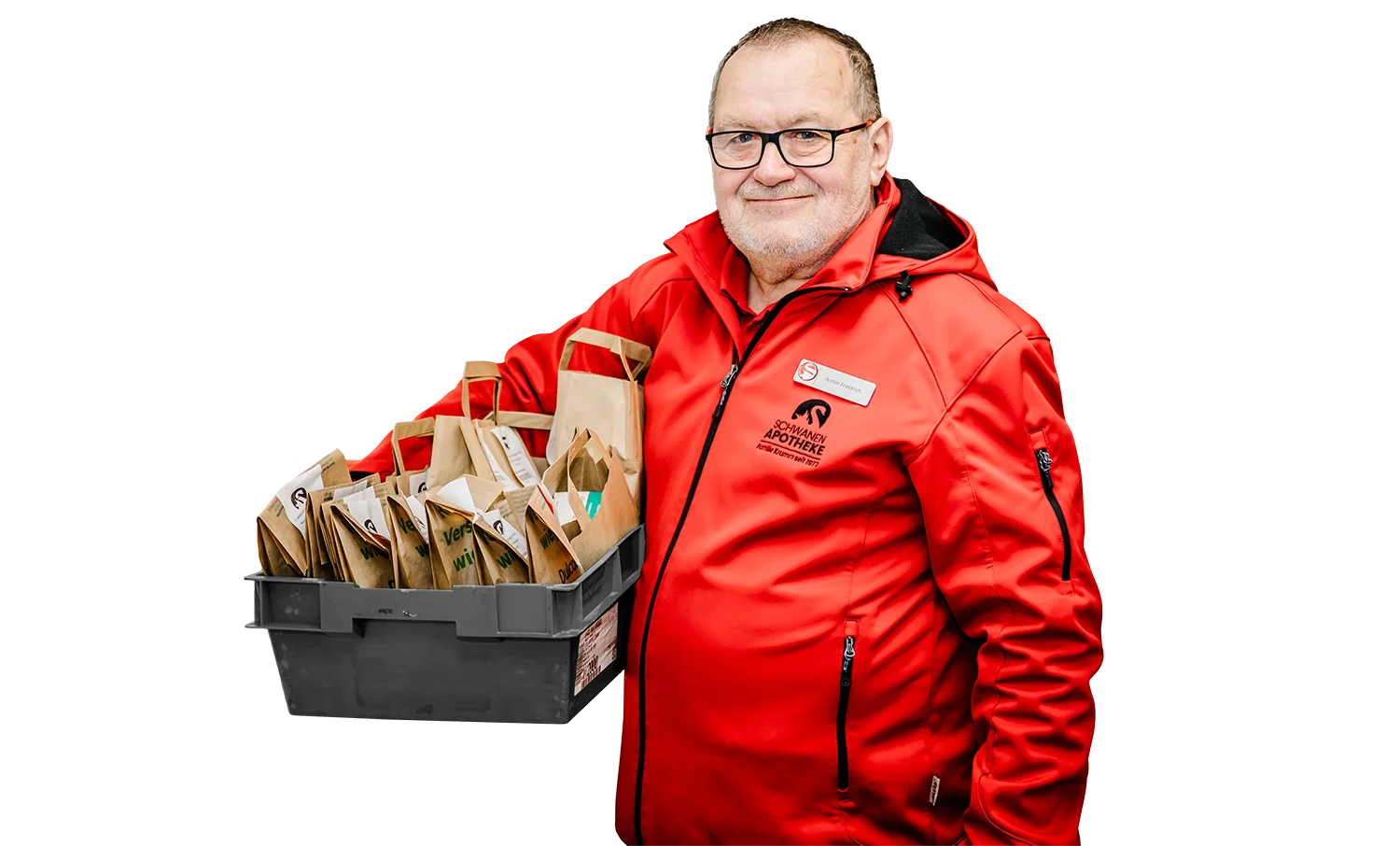Ein lächelnder Mann in einer roten Jacke hält eine schwarze Kiste voller Papiertüten für die Hauslieferungen. Auf der Jacke sind ein Logo und ein Namensschild angebracht. Der Hintergrund ist weiß.
